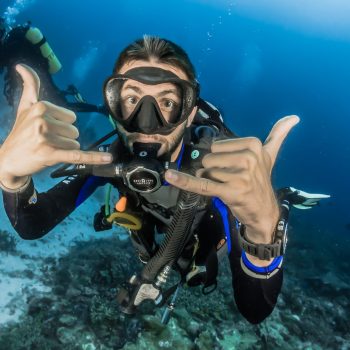 man underwater making hand signs
